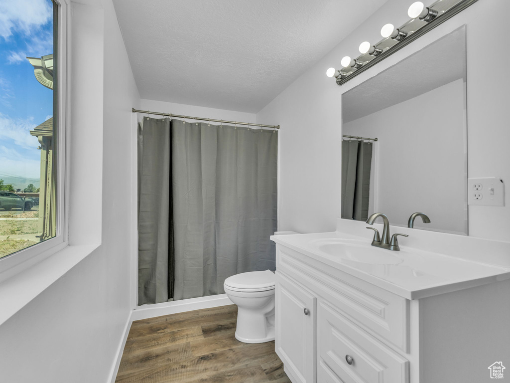 Full bathroom featuring vanity, wood finished floors, a shower with curtain, and a textured ceiling