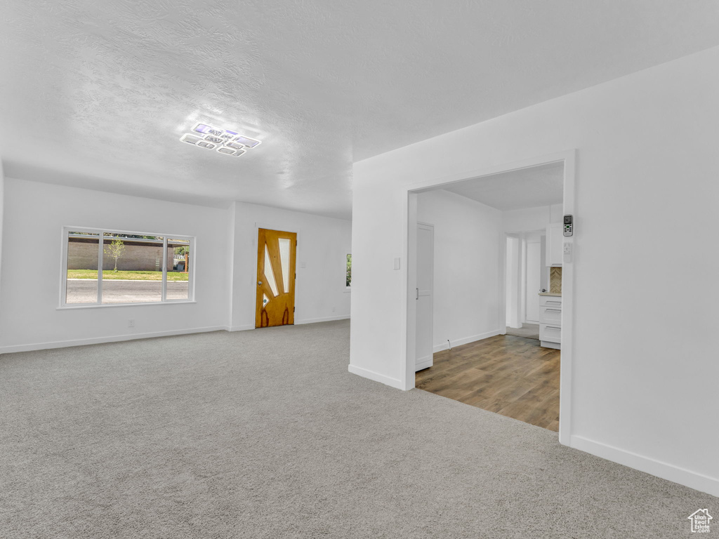 Unfurnished living room featuring carpet flooring and baseboards