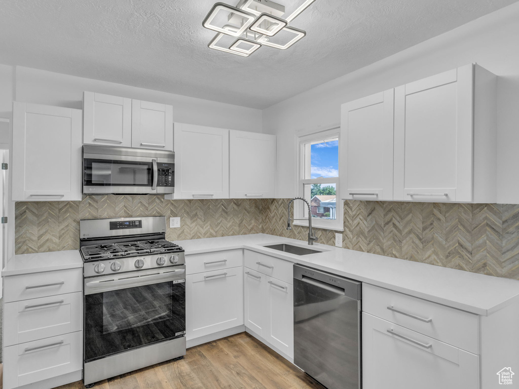 Kitchen featuring stainless steel appliances, light countertops, white cabinets, and a textured ceiling