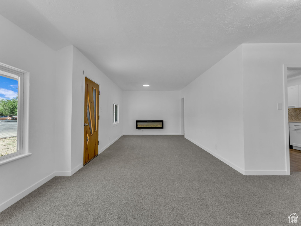 Unfurnished living room with carpet floors, a glass covered fireplace, and recessed lighting