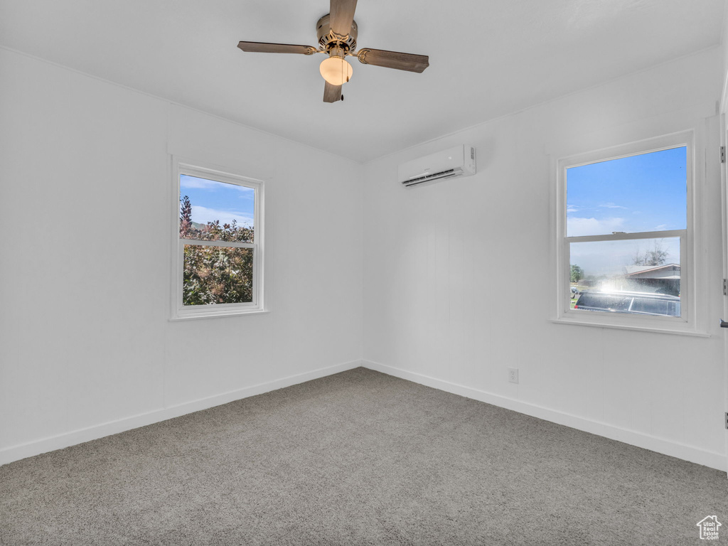 Carpeted empty room featuring a wall mounted AC and a ceiling fan