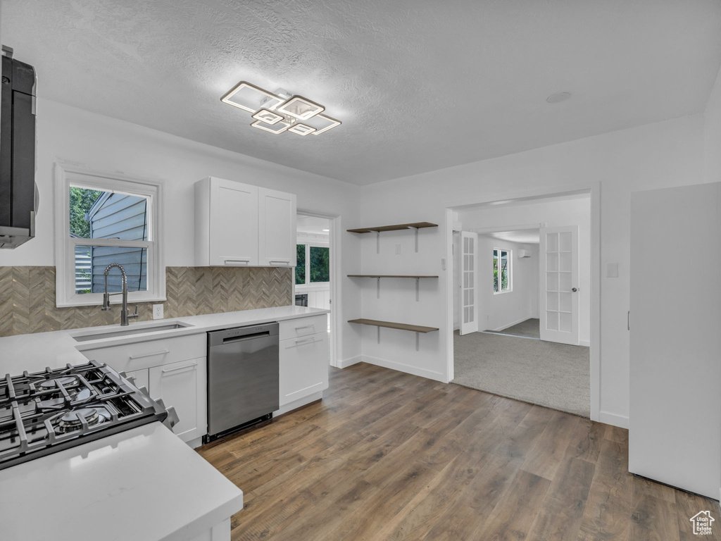 Kitchen featuring stainless steel dishwasher, light countertops, healthy amount of natural light, and a textured ceiling