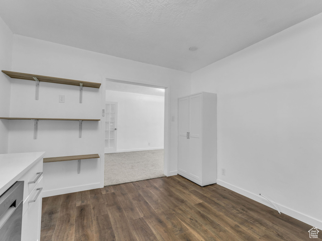 Spare room featuring dark wood-style flooring and baseboards