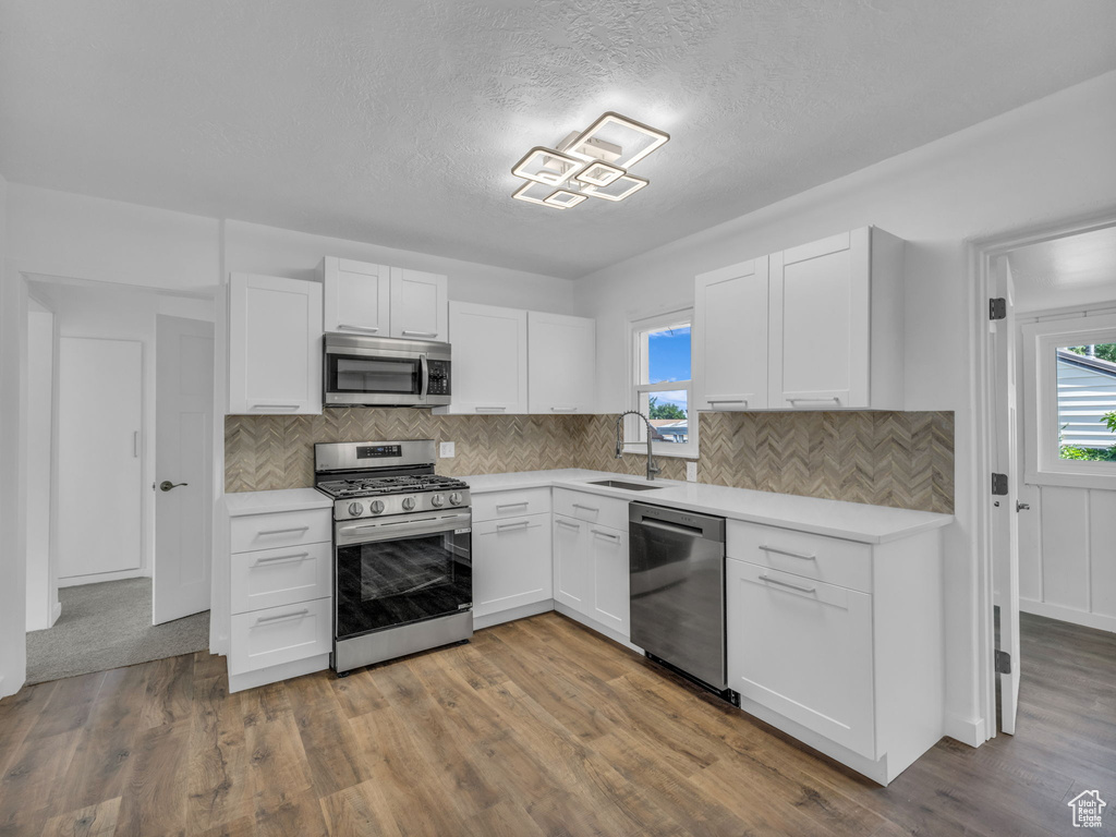 Kitchen featuring appliances with stainless steel finishes, healthy amount of natural light, light countertops, white cabinets, and a textured ceiling