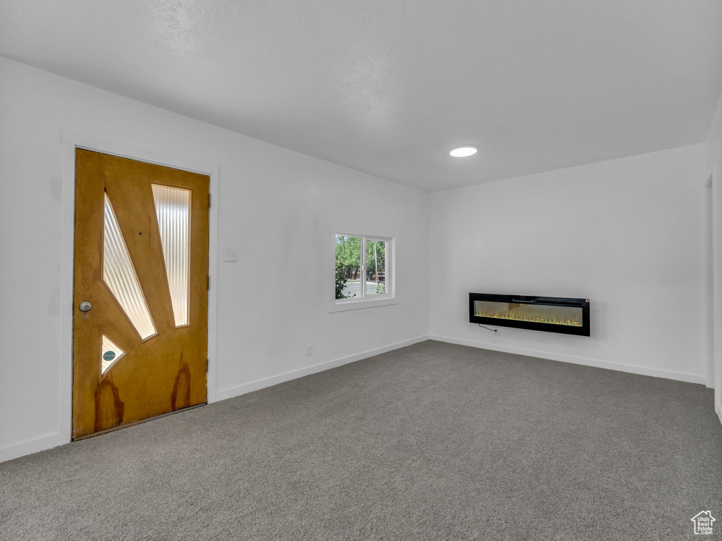 Unfurnished living room featuring carpet, a glass covered fireplace, and recessed lighting