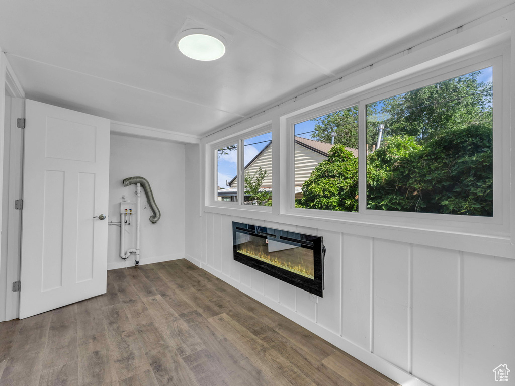 Unfurnished living room featuring a glass covered fireplace and wood finished floors