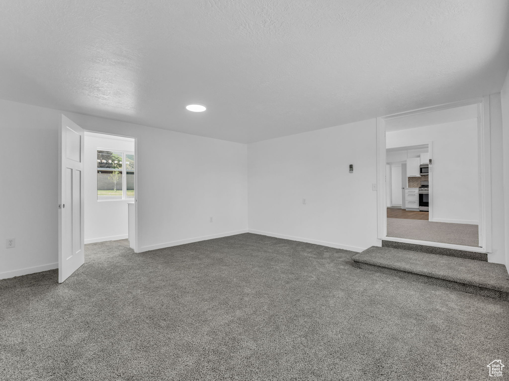 Unfurnished living room featuring carpet floors, a textured ceiling, and recessed lighting