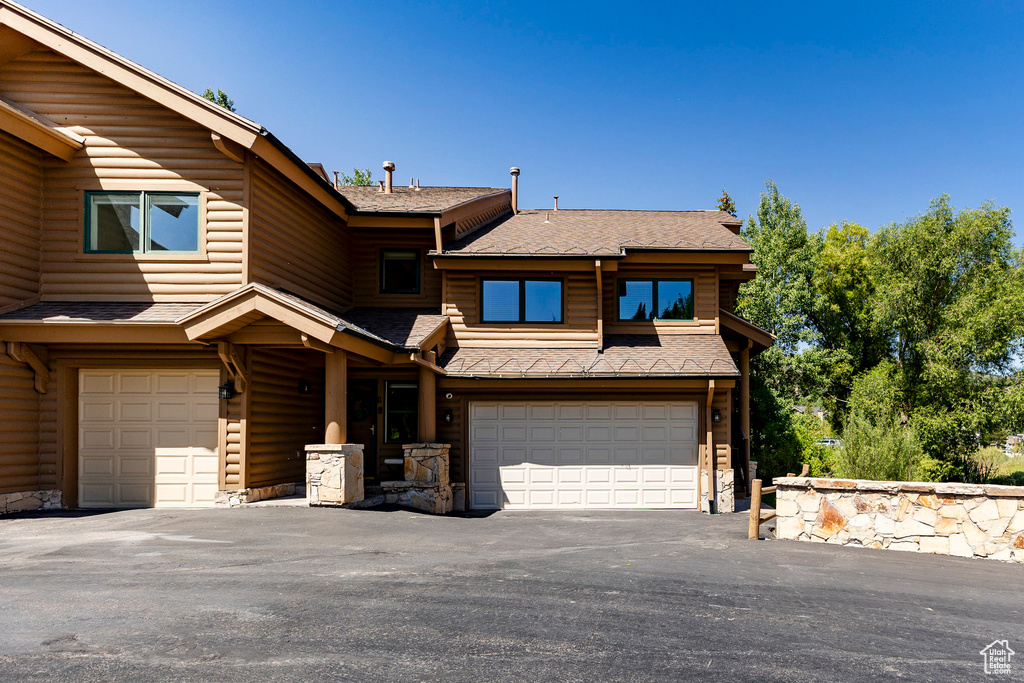 View of front of home featuring an attached garage, a shingled roof, and driveway