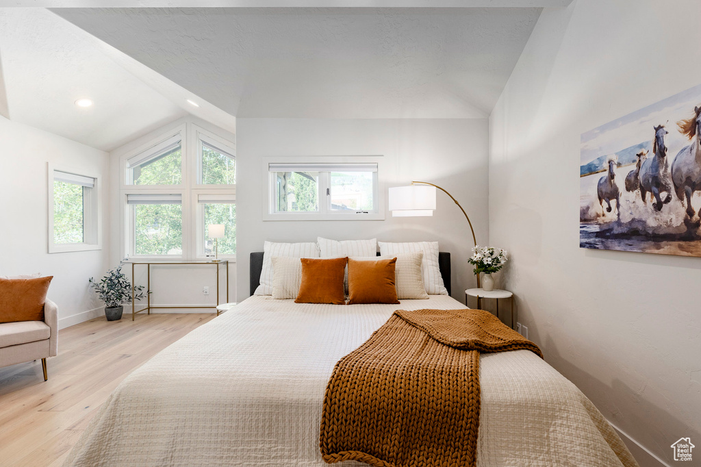 Bedroom with lofted ceiling, wood finished floors, multiple windows, and recessed lighting