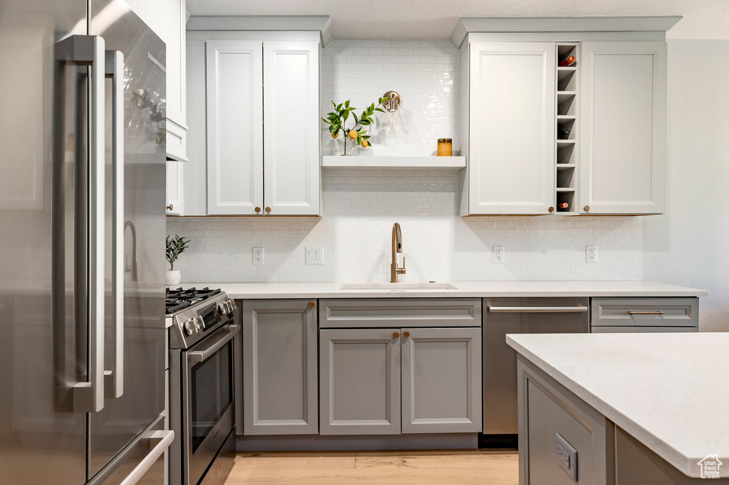 Kitchen featuring appliances with stainless steel finishes, open shelves, gray cabinetry, and backsplash