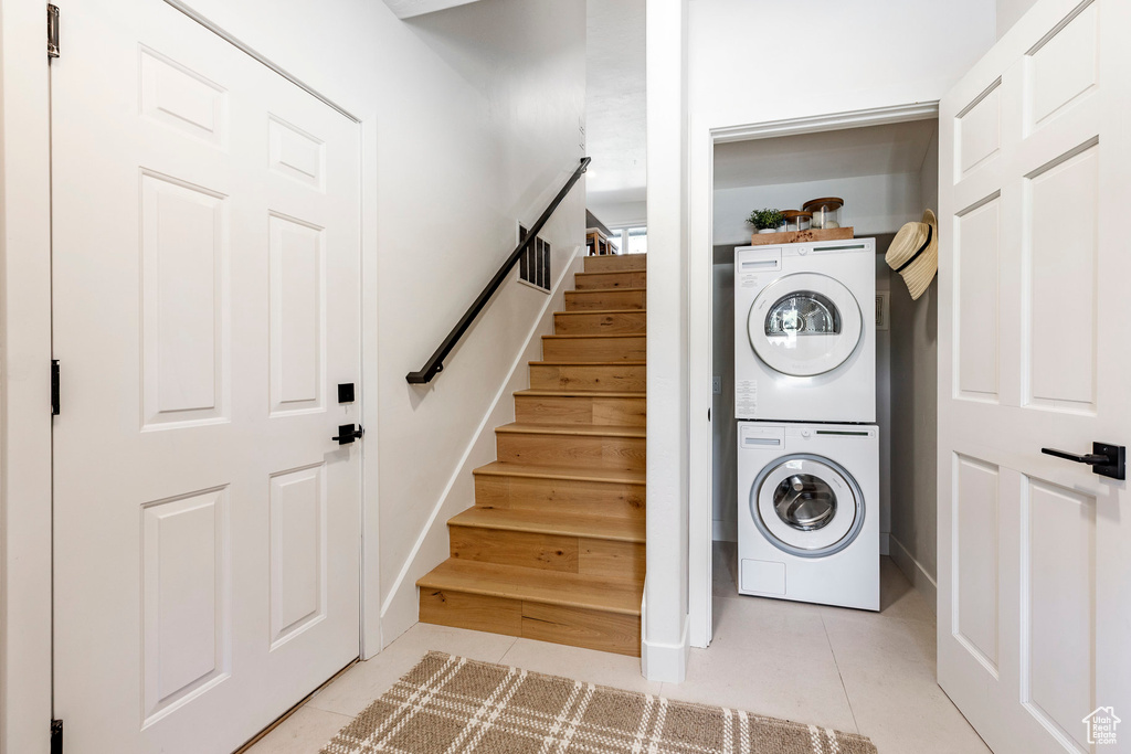 Laundry area featuring stacked washer / drying machine and light tile patterned floors