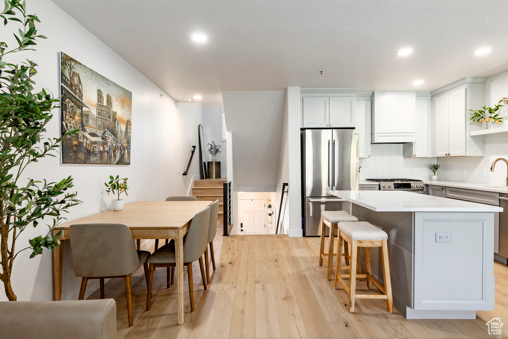 Kitchen featuring stainless steel appliances, recessed lighting, light wood-style flooring, light countertops, and a kitchen island
