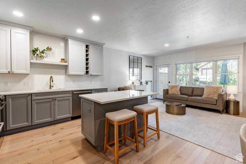 Kitchen with gray cabinets, open shelves, dishwasher, open floor plan, and decorative backsplash