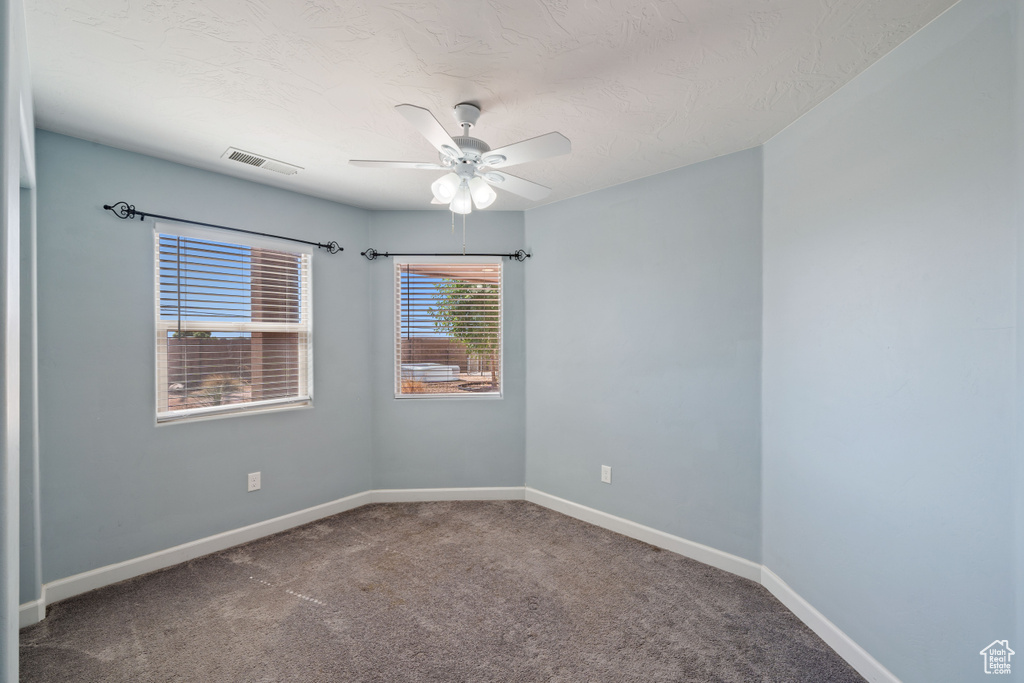 Carpeted empty room with ceiling fan and baseboards