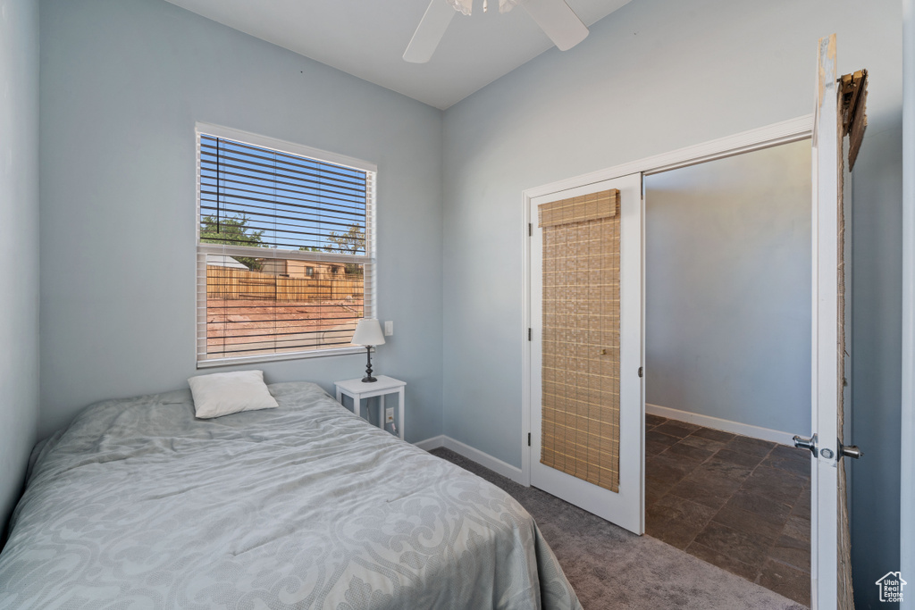 Bedroom featuring ceiling fan, dark colored carpet, and dark stone finish floors