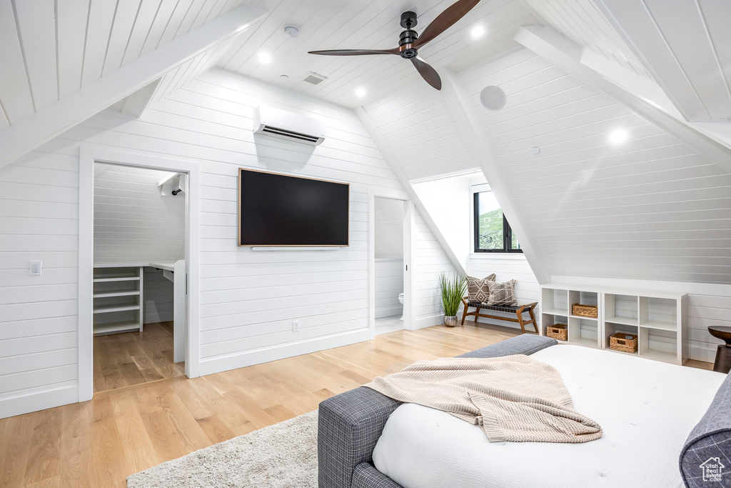 Bedroom featuring light wood-style floors, wood walls, a spacious closet, an AC wall unit, and wooden ceiling