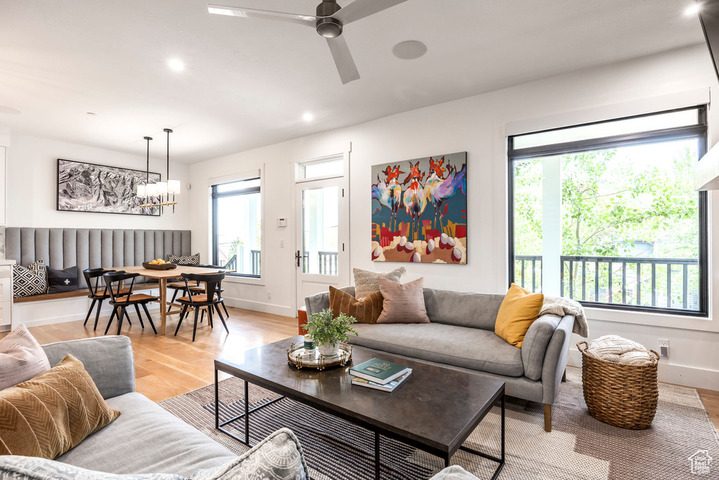 Living room featuring light wood finished floors, ceiling fan, a chandelier, and recessed lighting