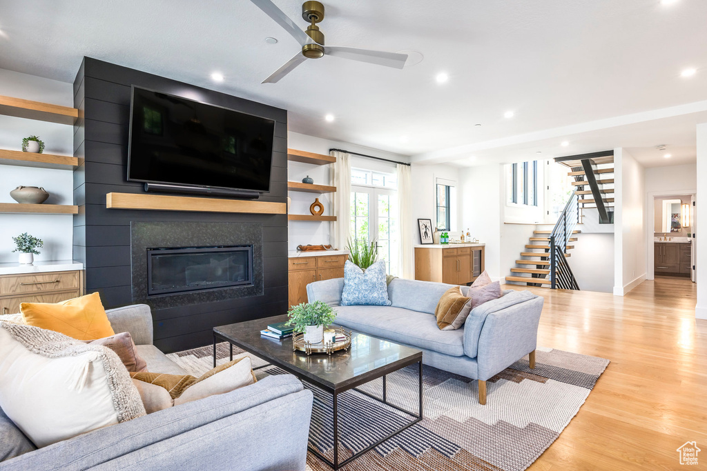 Living area featuring stairs, a fireplace, light wood finished floors, a ceiling fan, and recessed lighting