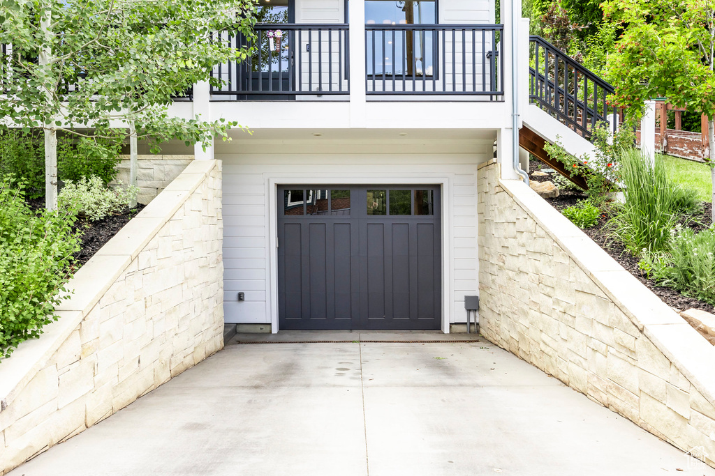 Doorway to property featuring an attached garage and concrete driveway