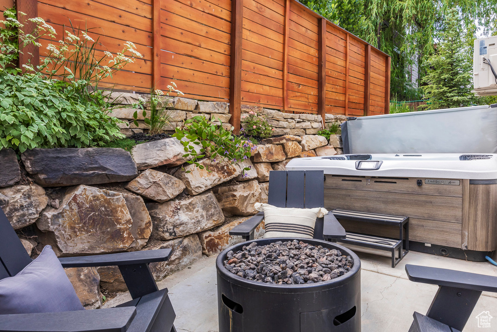 View of patio with a hot tub and an outdoor fire pit