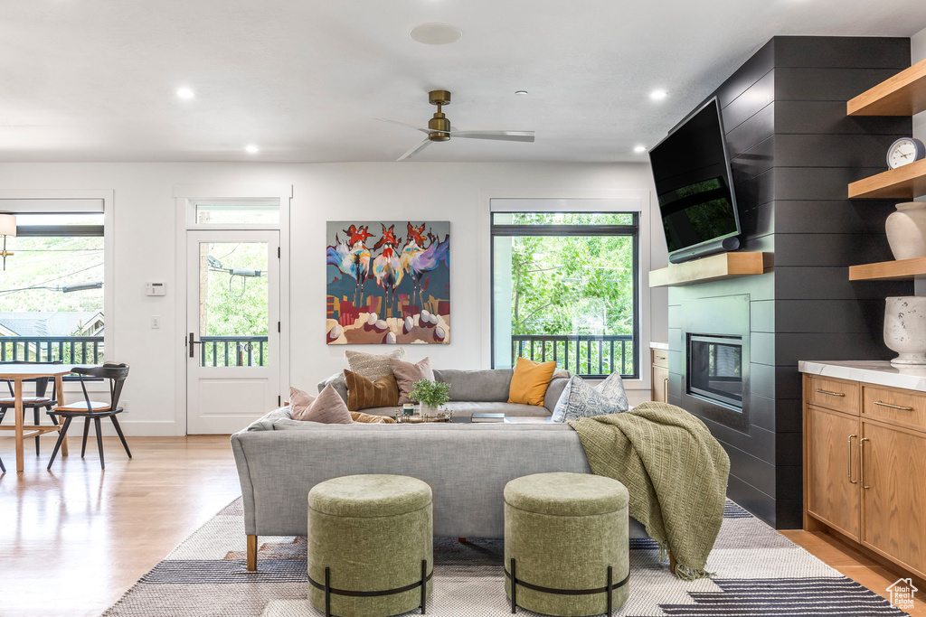 Living area with healthy amount of natural light, light wood-style floors, a ceiling fan, a large fireplace, and recessed lighting