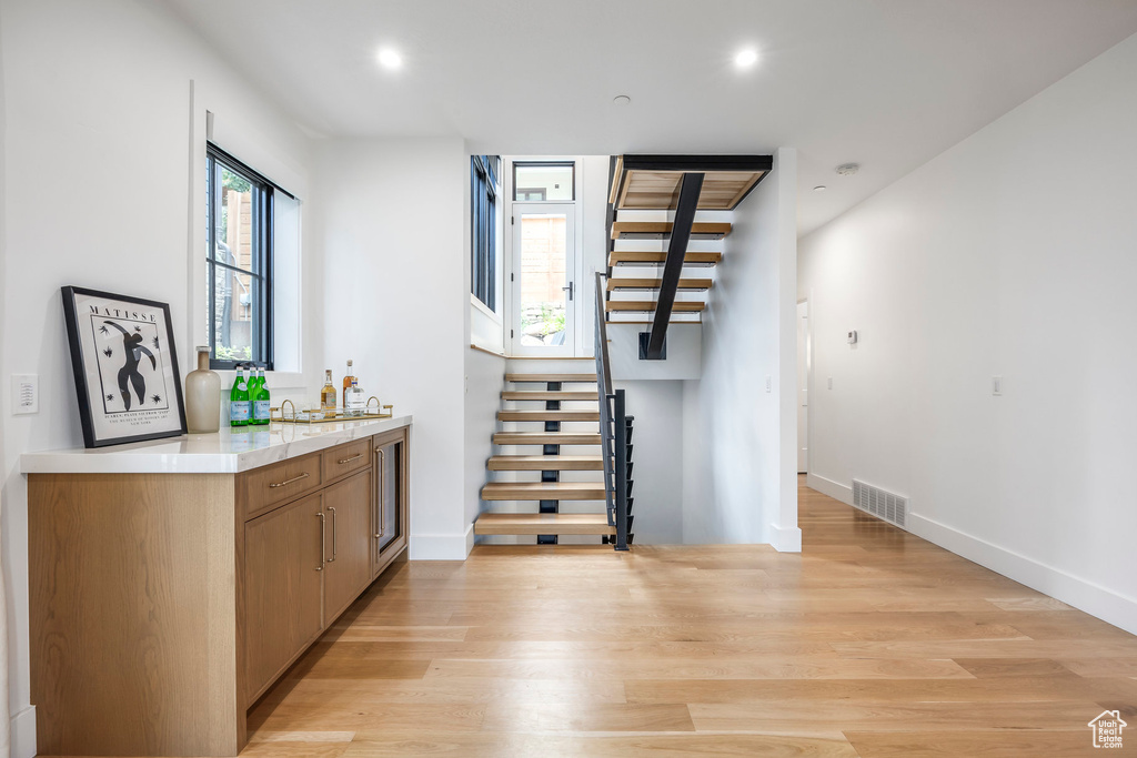 Indoor wet bar featuring stairs, light wood finished floors, and recessed lighting