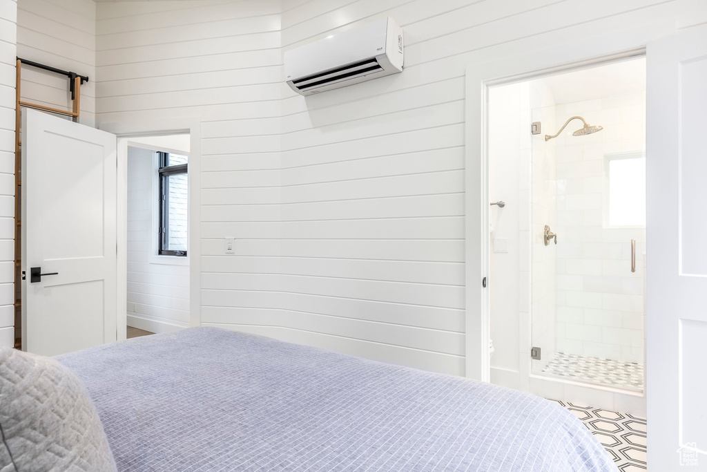 Bedroom featuring a wall mounted AC, a barn door, and wood walls