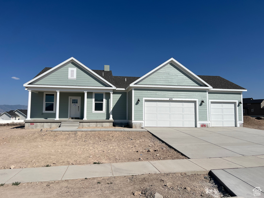 View of front of home featuring an attached garage, driveway, and a porch