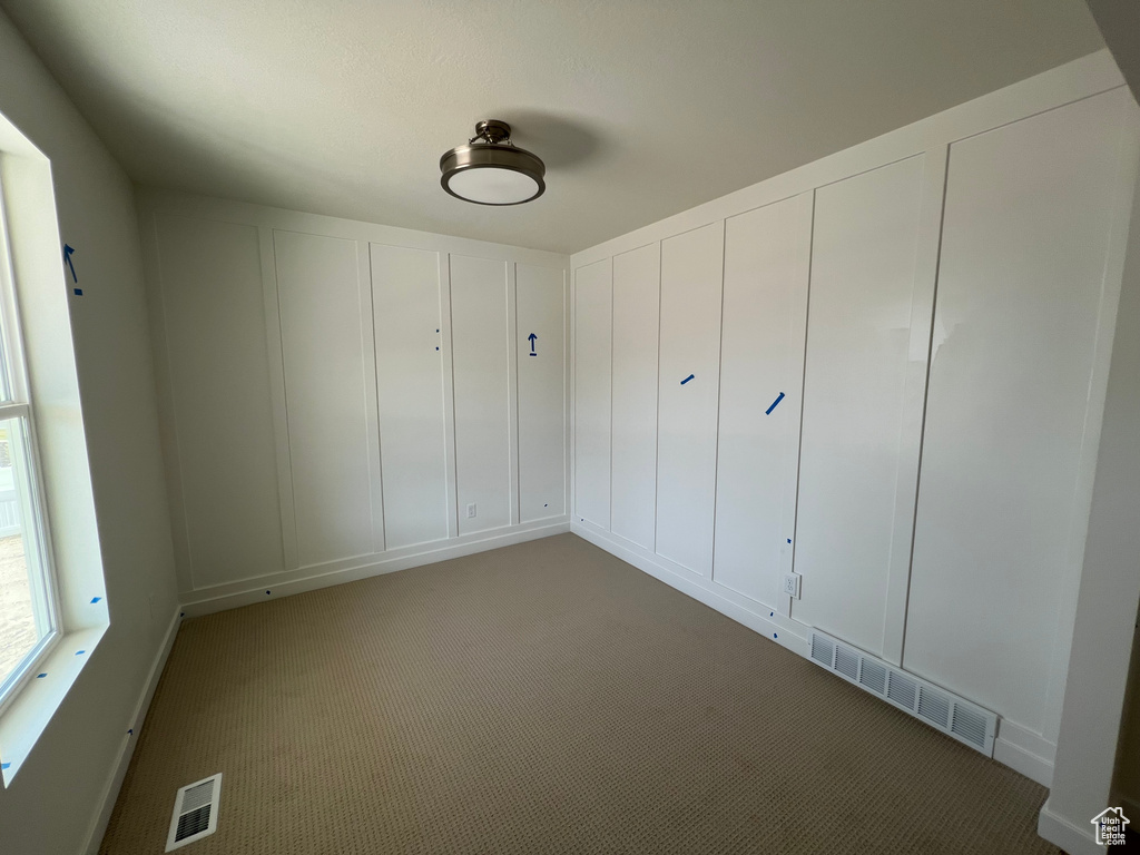 Spare room with dark carpet and a decorative wall