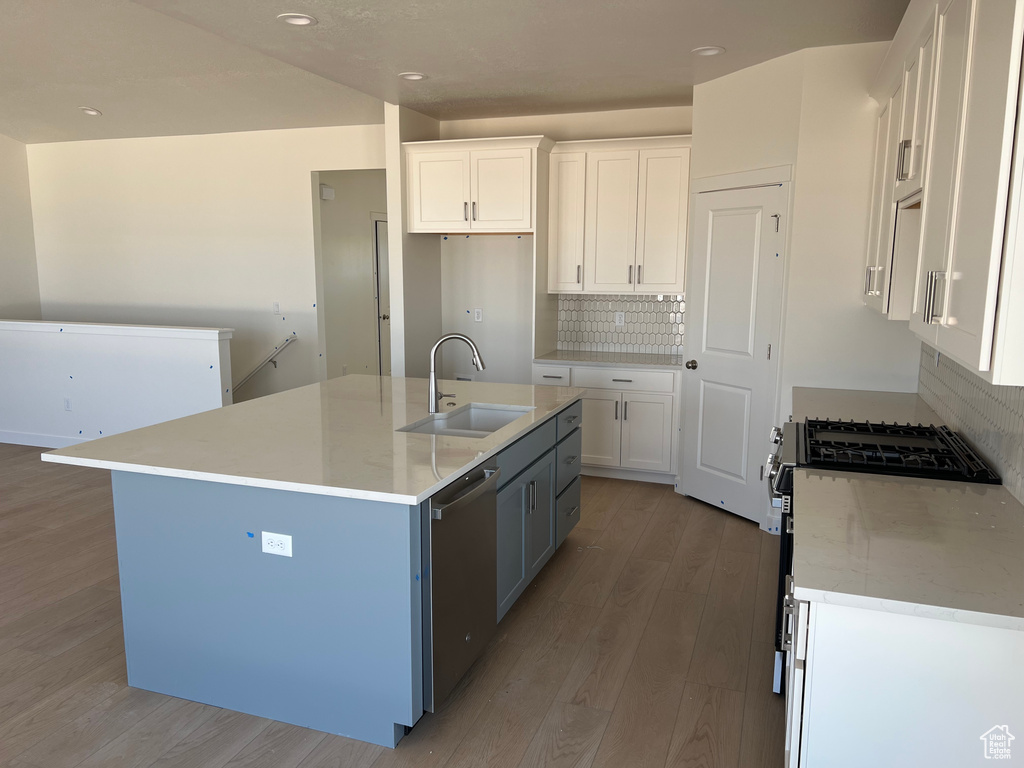 Kitchen featuring stainless steel appliances, light wood-type flooring, white cabinets, backsplash, and recessed lighting