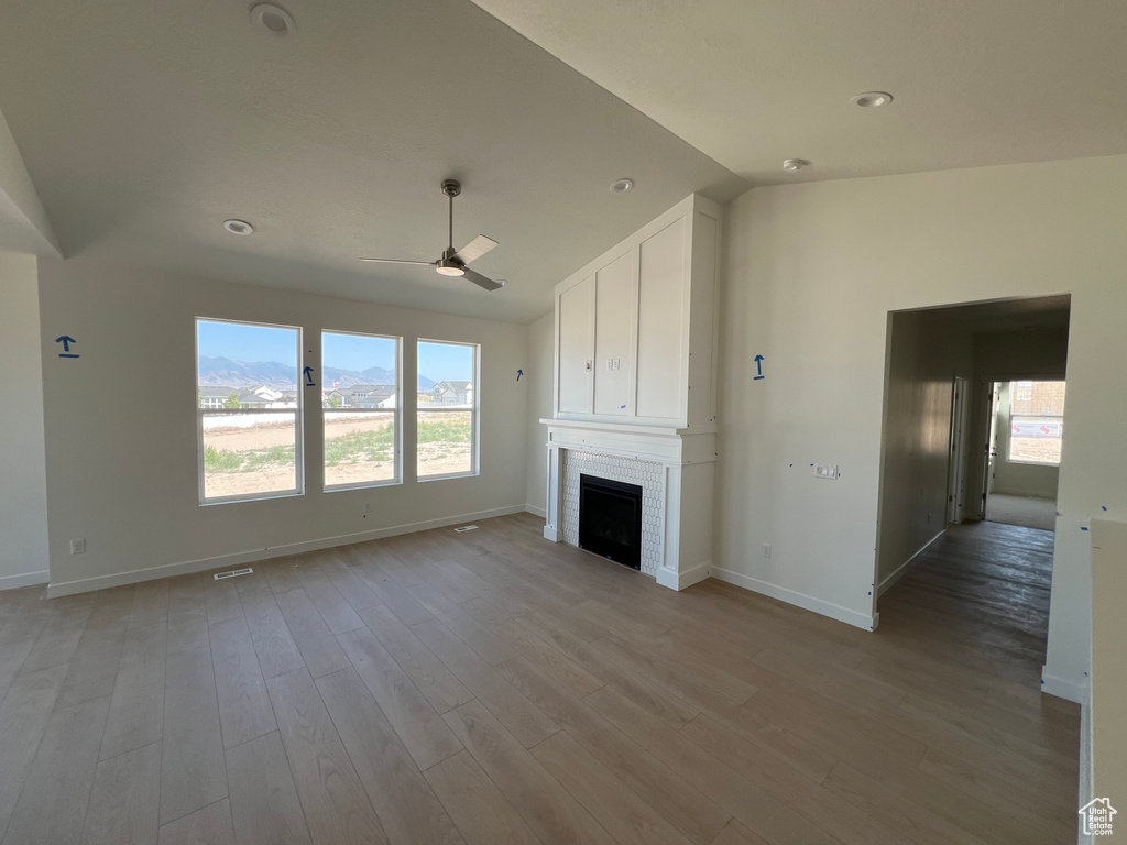 Unfurnished living room with a ceiling fan, a brick fireplace, vaulted ceiling, light wood-style flooring, and recessed lighting