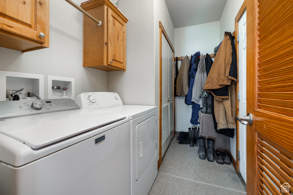 Laundry room featuring cabinet space, washer and dryer, and light colored carpet