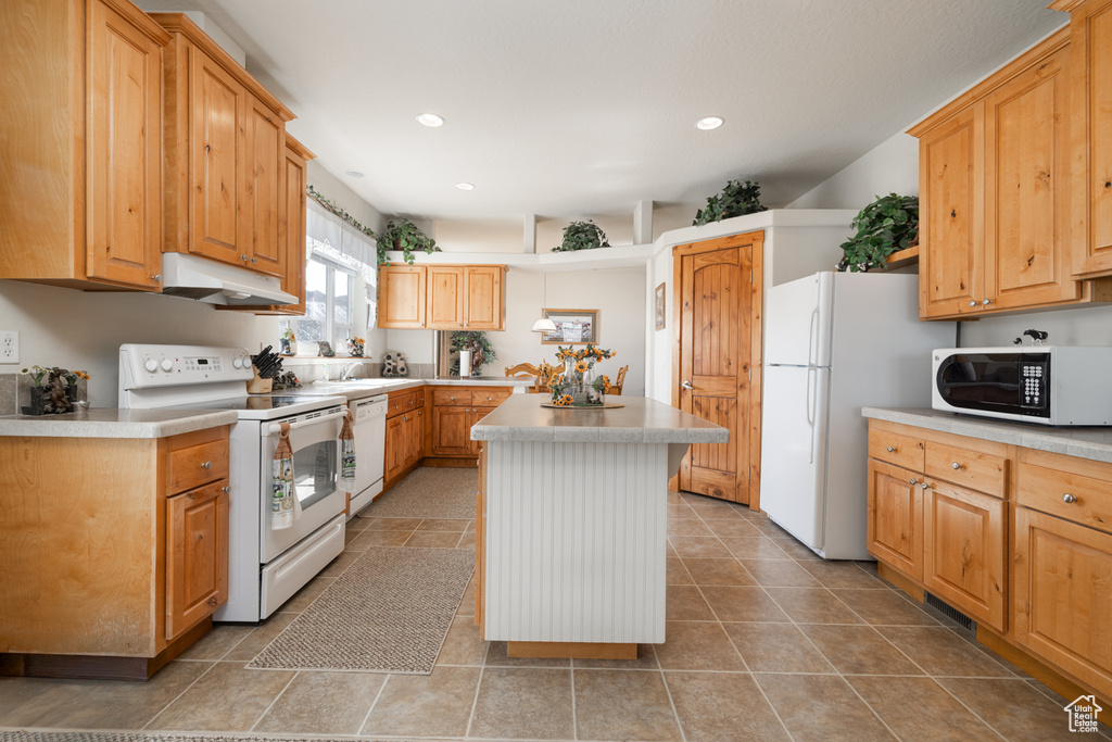 Kitchen with white appliances, under cabinet range hood, a center island, light countertops, and recessed lighting