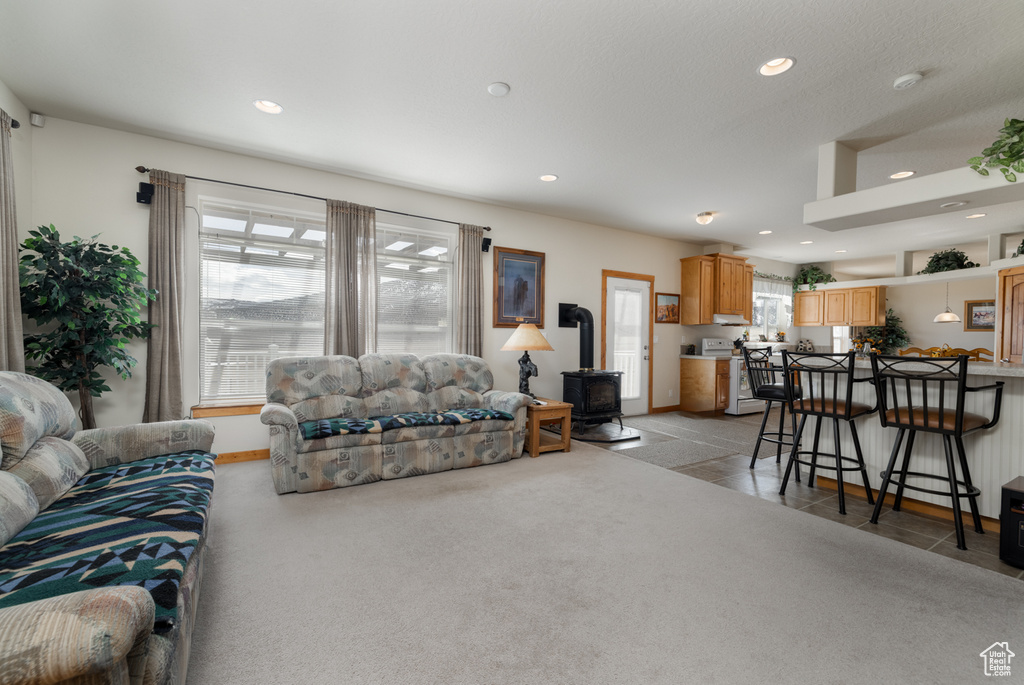 Living room with a wood stove, recessed lighting, and light carpet
