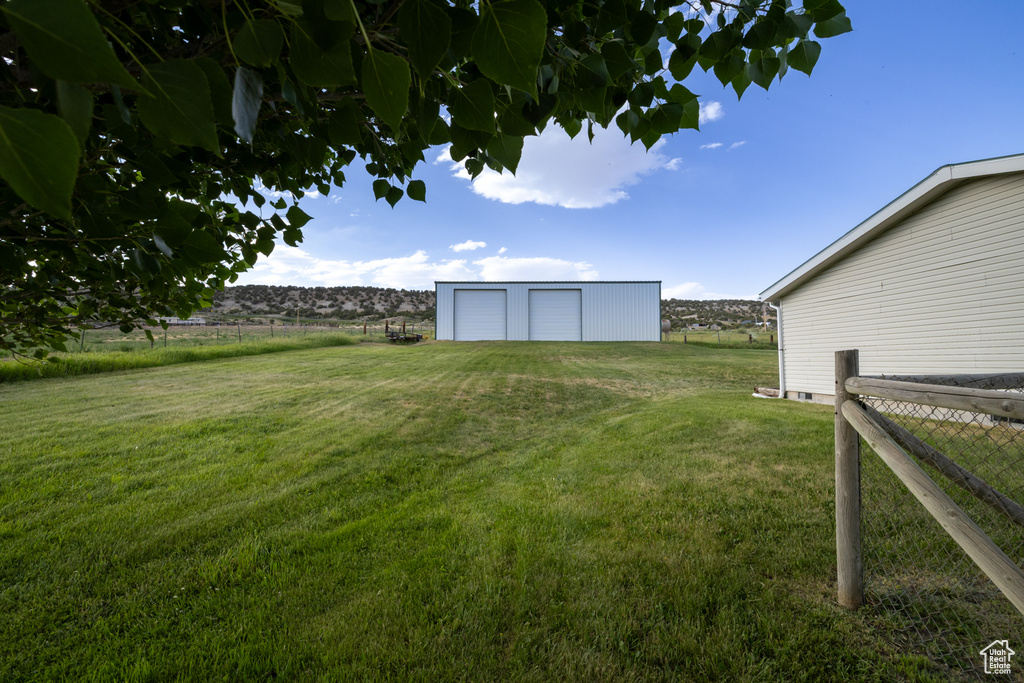 View of yard featuring a detached garage, an outdoor structure, and a view of countryside