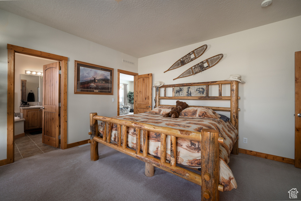 Bedroom featuring carpet flooring, ensuite bath, and a textured ceiling