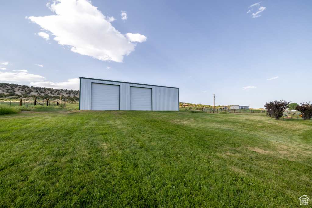 View of grassy yard featuring a garage, an outbuilding, and a view of countryside