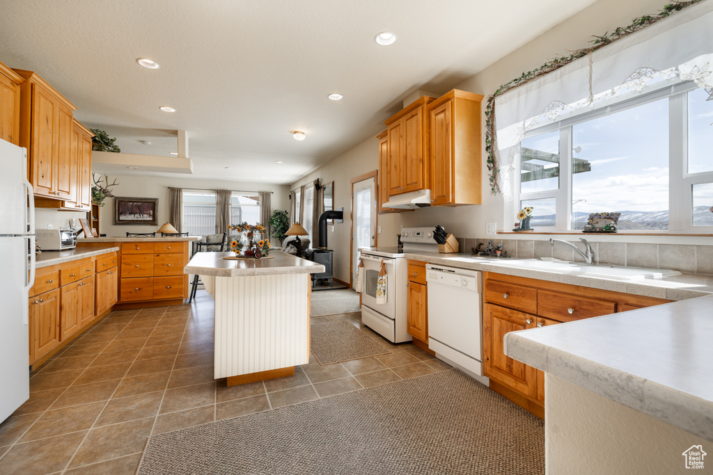 Kitchen featuring white appliances, under cabinet range hood, recessed lighting, light tile patterned floors, and light countertops