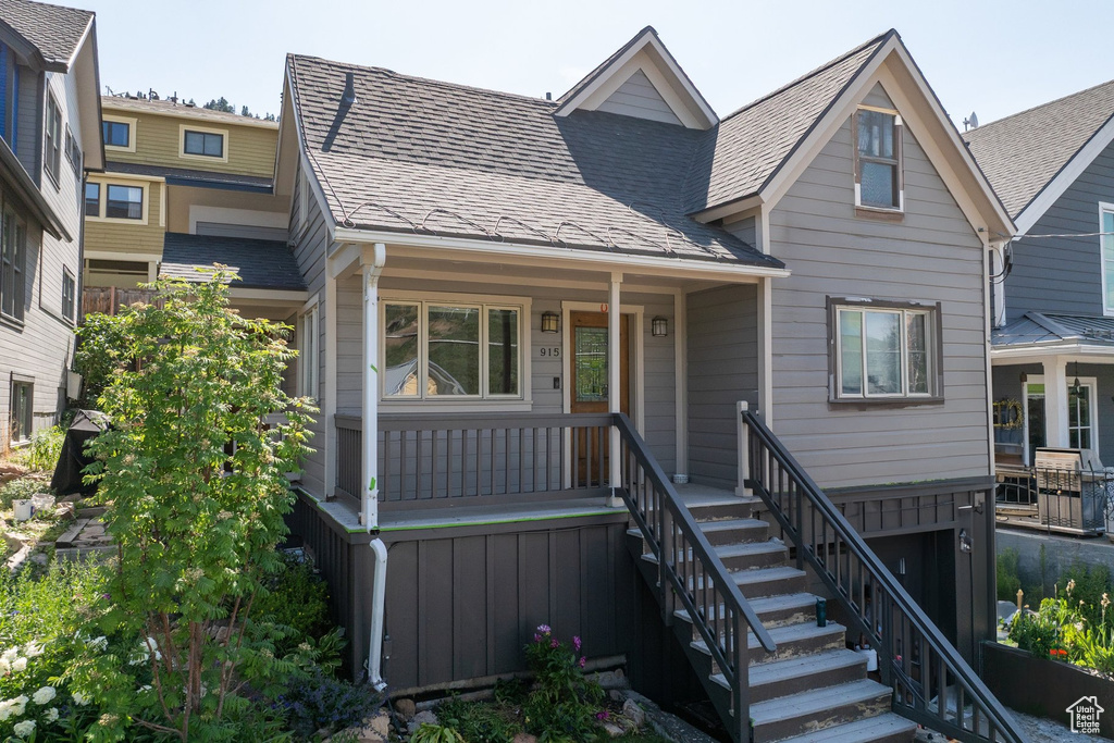 View of front of house with a porch, a shingled roof, and stairway