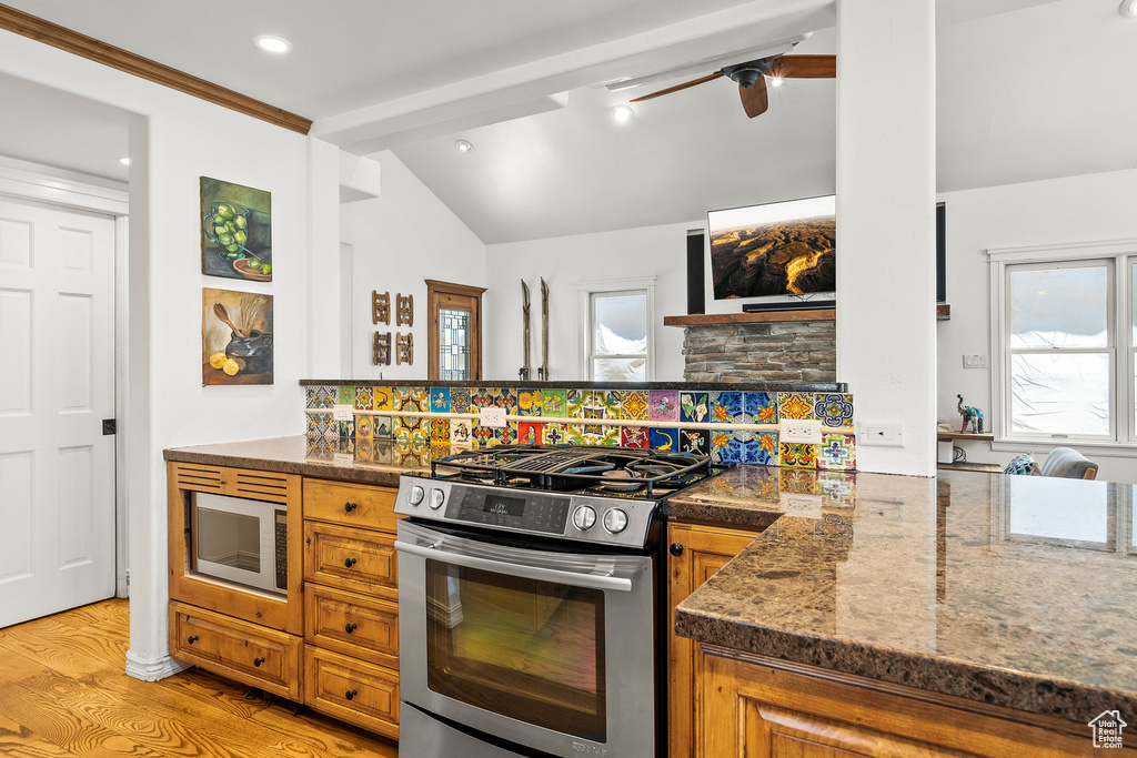 Kitchen with stainless steel gas stove, brown cabinetry, light wood finished floors, a peninsula, and recessed lighting