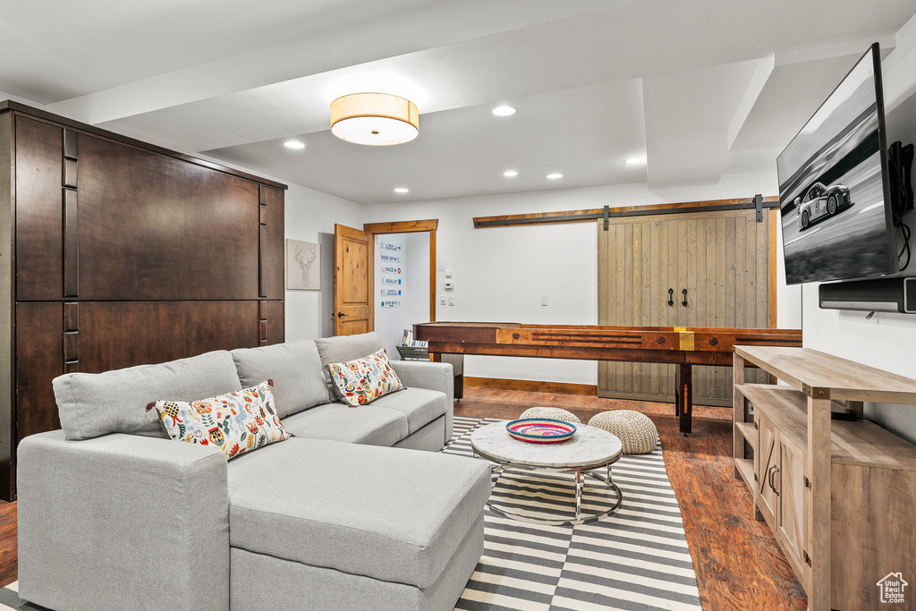 Living room with dark wood finished floors, recessed lighting, and a barn door