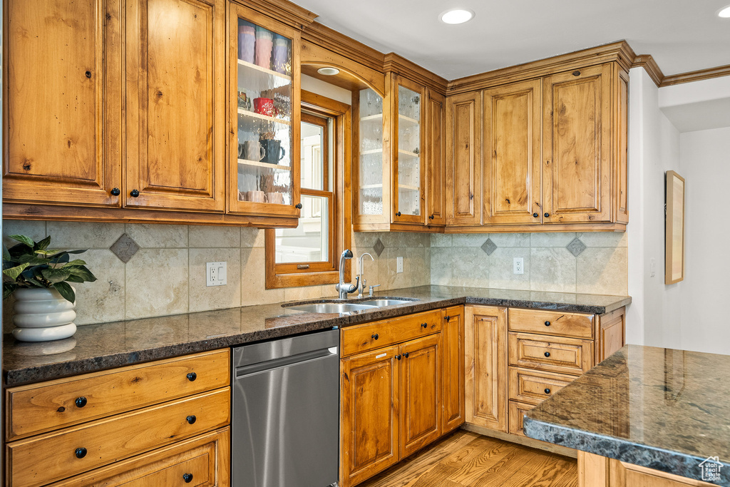 Kitchen featuring stainless steel dishwasher, light wood-type flooring, brown cabinets, glass insert cabinets, and recessed lighting