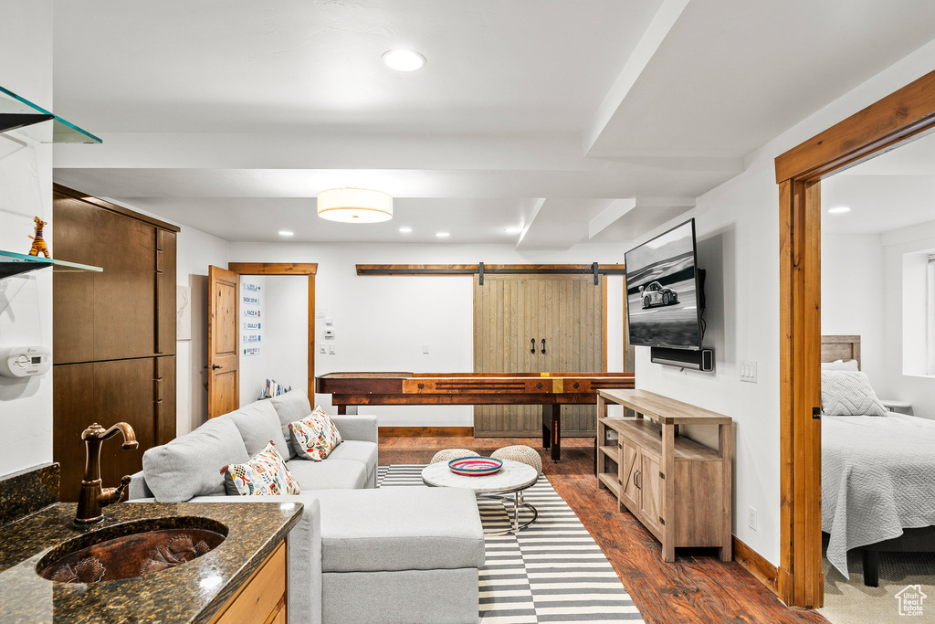 Living room featuring a barn door, dark wood finished floors, and recessed lighting