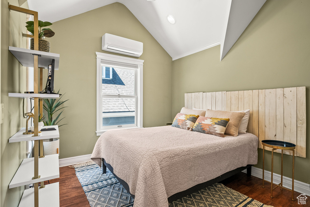 Bedroom featuring a wall unit AC, lofted ceiling, and wood finished floors