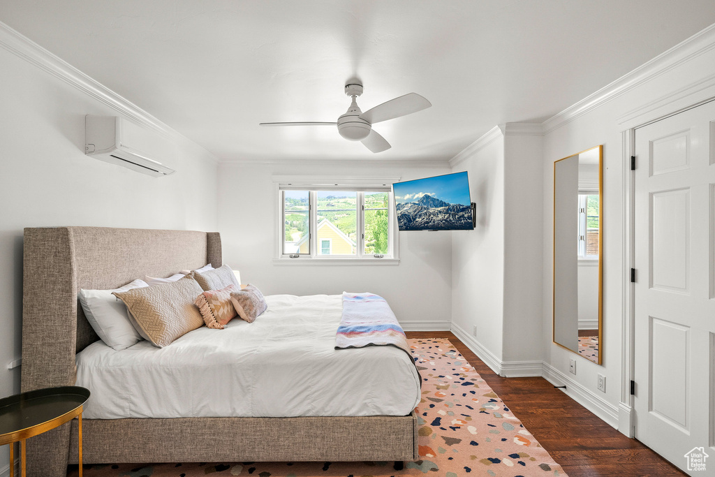 Bedroom with an AC wall unit, crown molding, wood finished floors, and a ceiling fan
