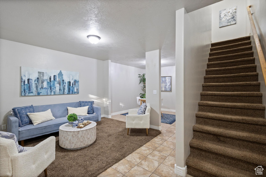 Living area featuring stairway, light tile patterned flooring, and a textured ceiling