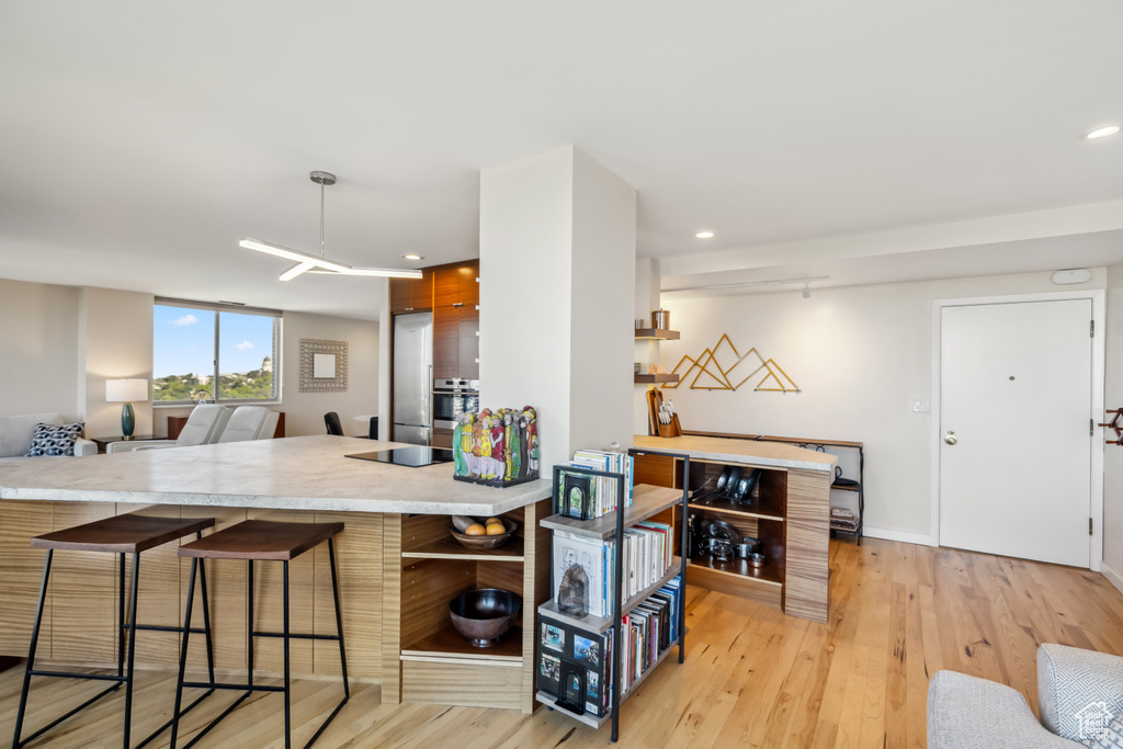 Kitchen featuring a kitchen bar, light wood-style flooring, light countertops, recessed lighting, and oven