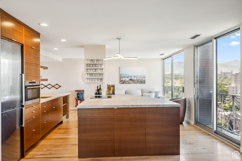 Kitchen featuring stainless steel appliances, light wood-style flooring, modern cabinets, brown cabinets, and recessed lighting
