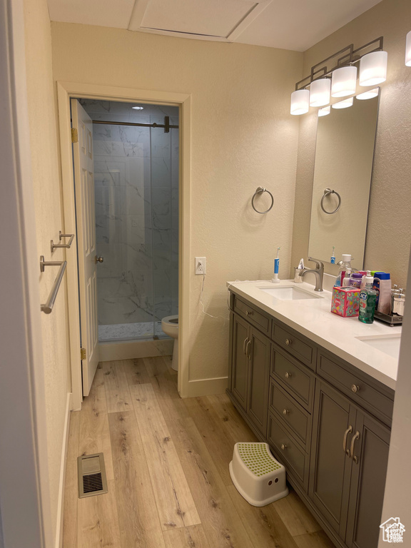 Full bath featuring wood finished floors, a marble finish shower, and double vanity