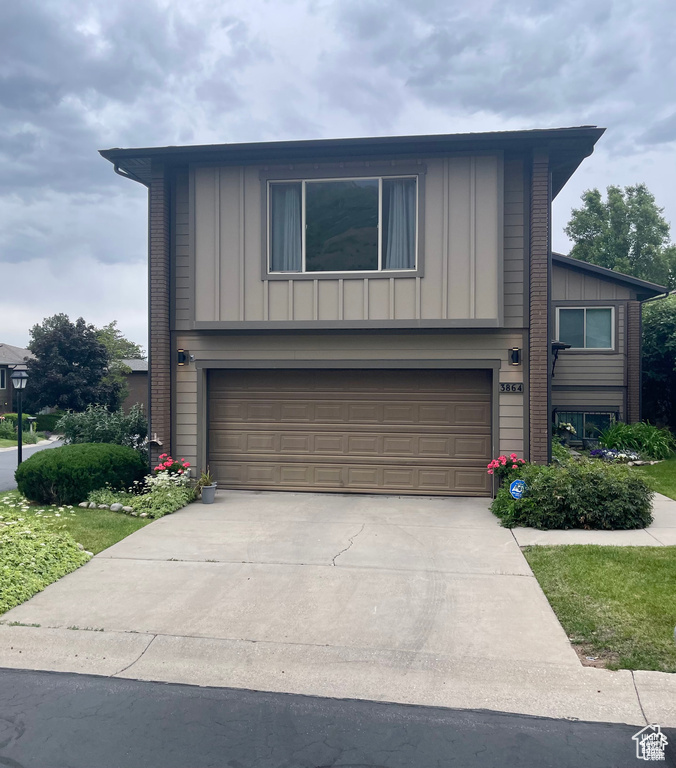View of front of house with board and batten siding, a garage, and concrete driveway